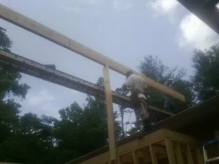 Carpenter setting a ridge beam over a new addition frame — Ice Dam Removal by Roofing Brothers in Harlingen