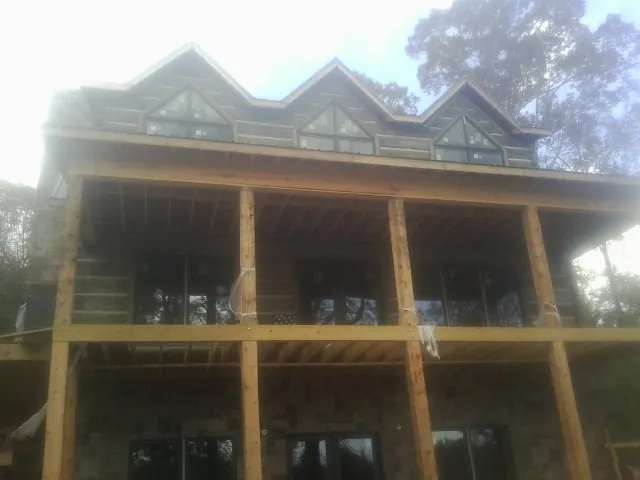 Dormers and porch framing on a large log home under construction — Roof Coating work by our crew in Harlingen