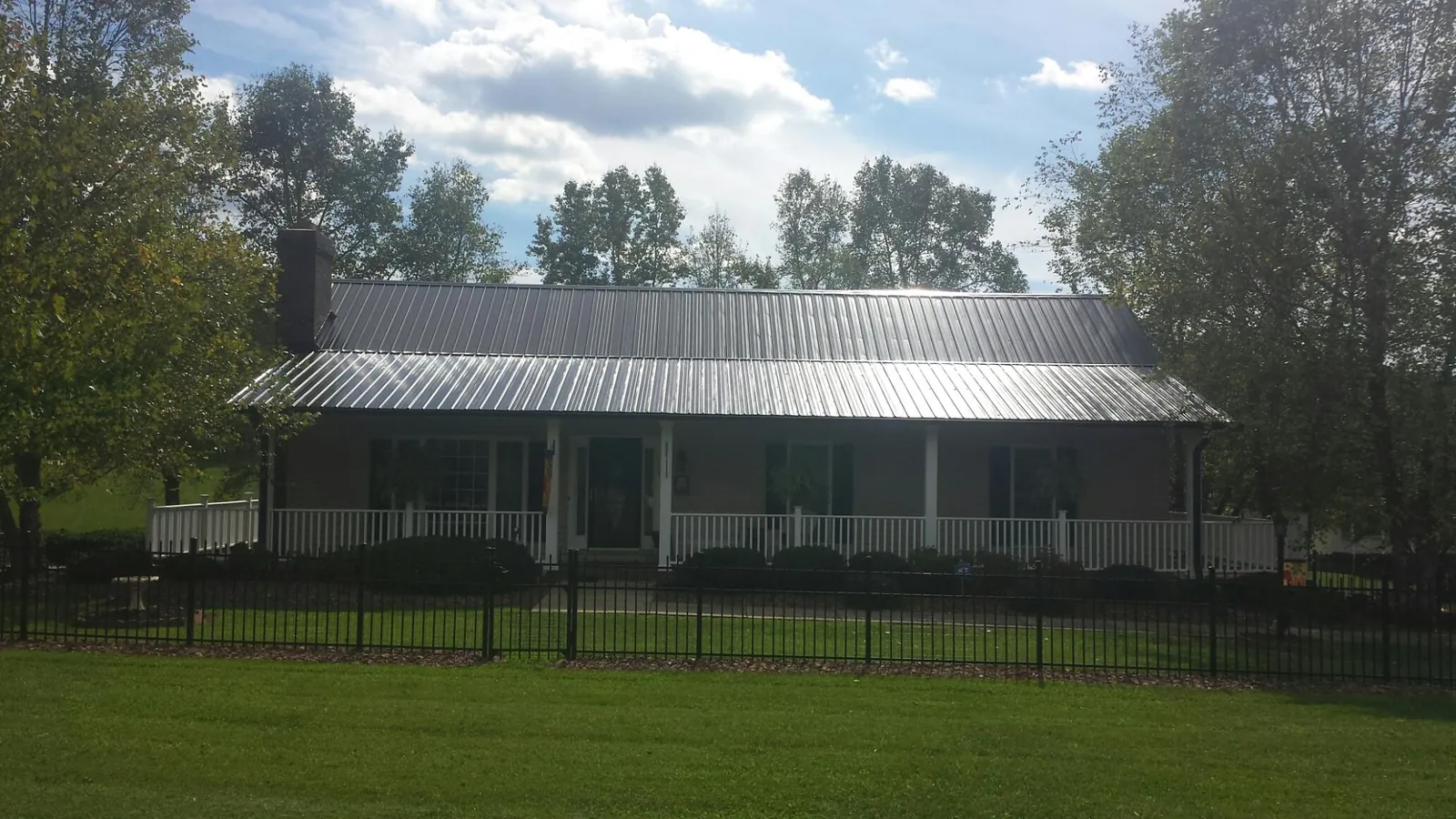 Gray metal roof on a brick ranch with a full width front porch — Gutter Guard Installation work by our crew in Harlingen