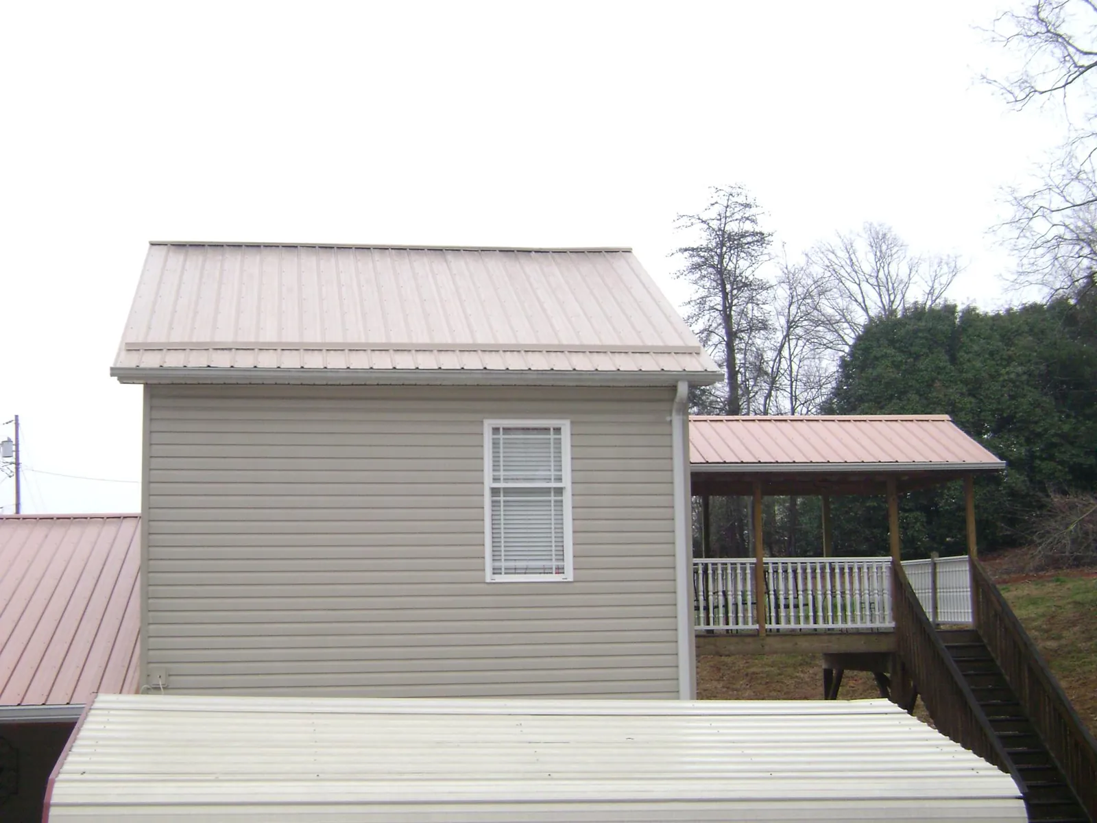 Tan metal roofs on a two story addition and attached porch, from a Roof Replacement job in Harlingen