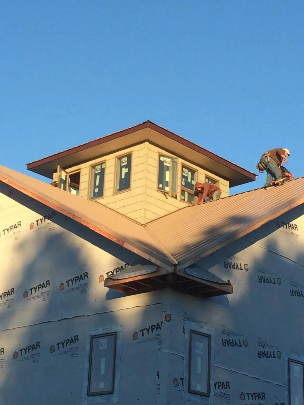 Roofers working around a rooftop cupola on a new metal roof at sunset — Roof Waterproofing in Harlingen by Roofing Brothers